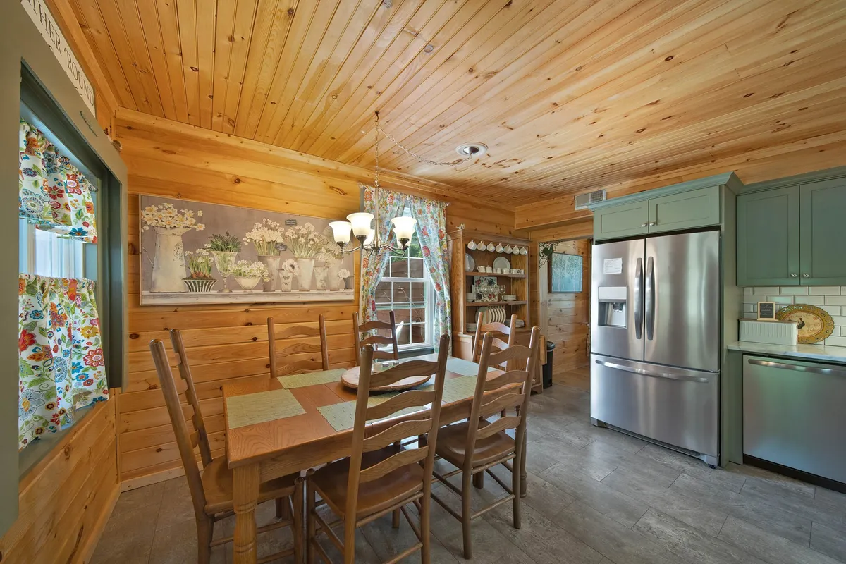 A dining area with a sturdy wooden table, colorful curtains, modern kitchen appliances, and unique wall art. The setup is ideal for both casual family meals and more festive gatherings, reflecting the communal spirit mentioned in the section.