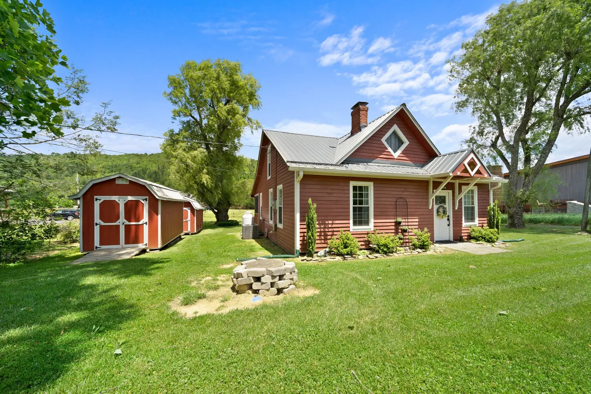 This exterior image showcases a peaceful scene featuring a charming red house surrounded by a lush garden and a storage shed. The setting is ideal for various outdoor activities such as gardening, family gatherings, and children’s play. The inviting porch area suggests enjoying sunsets and relaxing outdoors during all seasons.