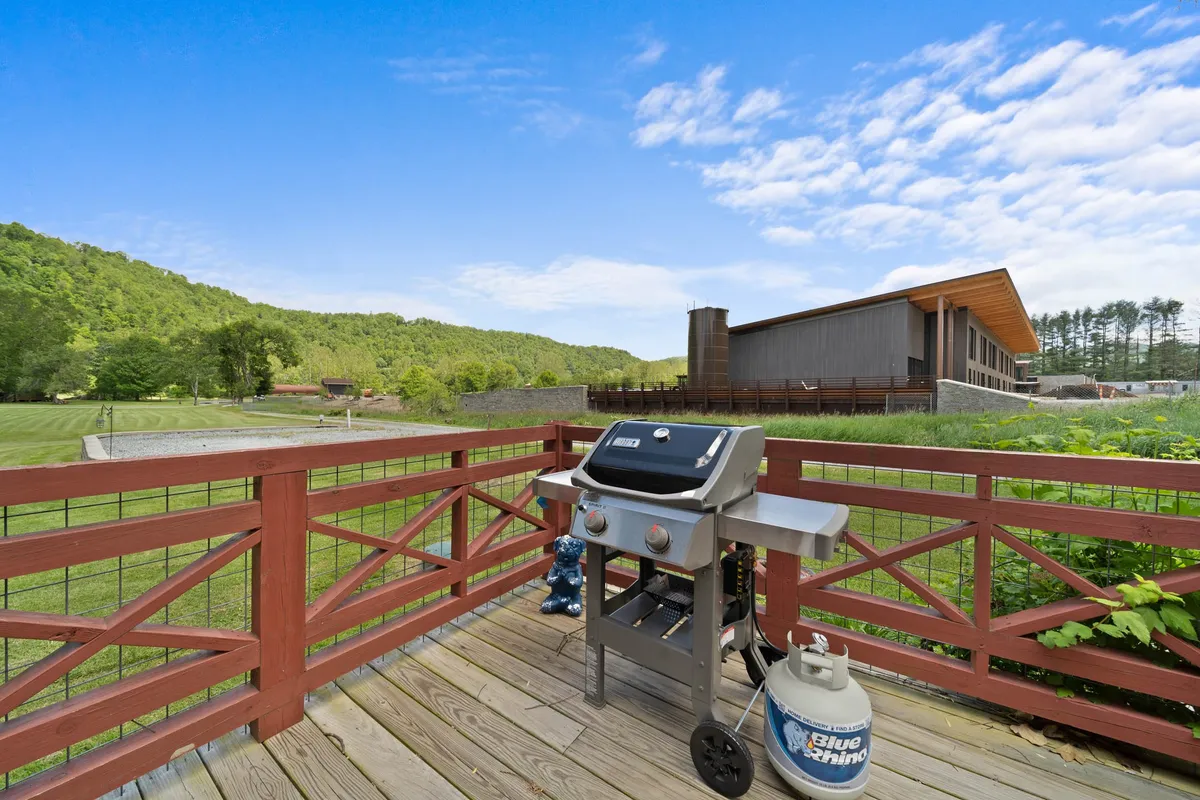 The image highlights a spacious deck equipped with a grill and scenic views of the mountains beyond the railing. The setup suggests opportunities for barbecuing, outdoor dining, and group gatherings, all with the bonus of stunning nature views.